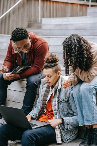 three friends sharing laptop on outdoor stairs Photo by Keira Burton from Pexels